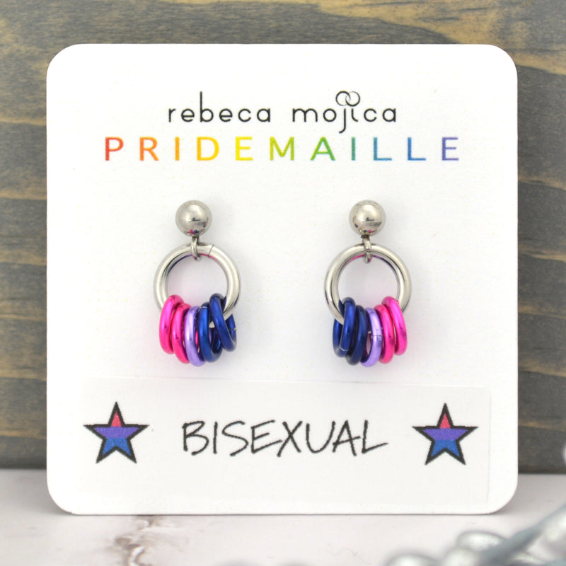 Small bisexual pride chainmaille stud earrings on a white card. Each earring has a stainless steel ball with a steel link and 5 smaller links in the colors of the bi pride flag - 2 pink, lilac and 2 blue