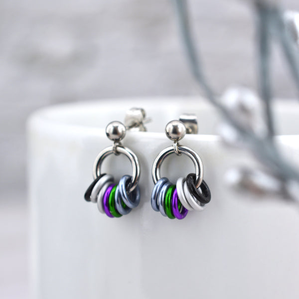 Small double demi pride chainmaille stud earrings on a white card. Each earring has a stainless steel ball with a steel link and 7 smaller links in the colors of the double demi pride flag - black, 2 white, violet, green and 2 light grey