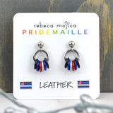 A pair of tiny leather pride chainmaille earrings dislayed on a small white card. Earrings have a small stainless steel ball at the top of each post, with a medium size steel ring hanging from the ball. Small anodized aluminum jump rings hang from the medium steel ring in colors to best match the leather/kink pride flag: black, blue, red, white, blue and black. The colors appear in mirror image on each earring. Earring card has text rebeca mojica PRIDEMAILLE Leather