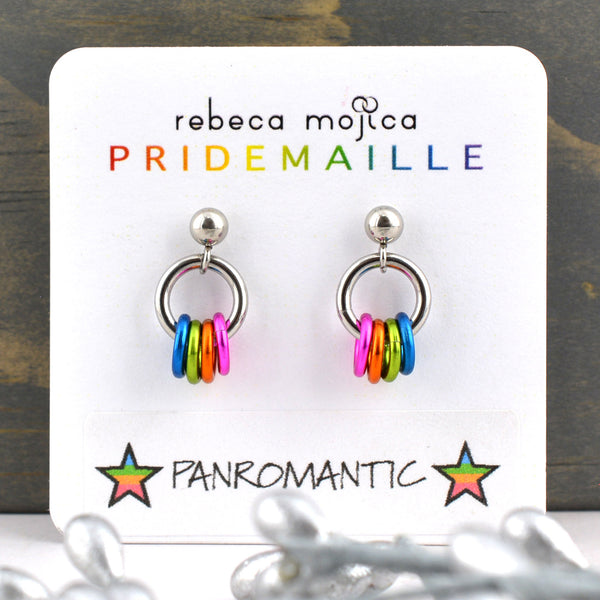 Tiny lgbtq panromantic pride chainmaille stud earrings on a white card. Each earring has a stainless steel ball with a steel link and 4 smaller links in the colors of the panromantic pride flag - blue, green, orange and pink