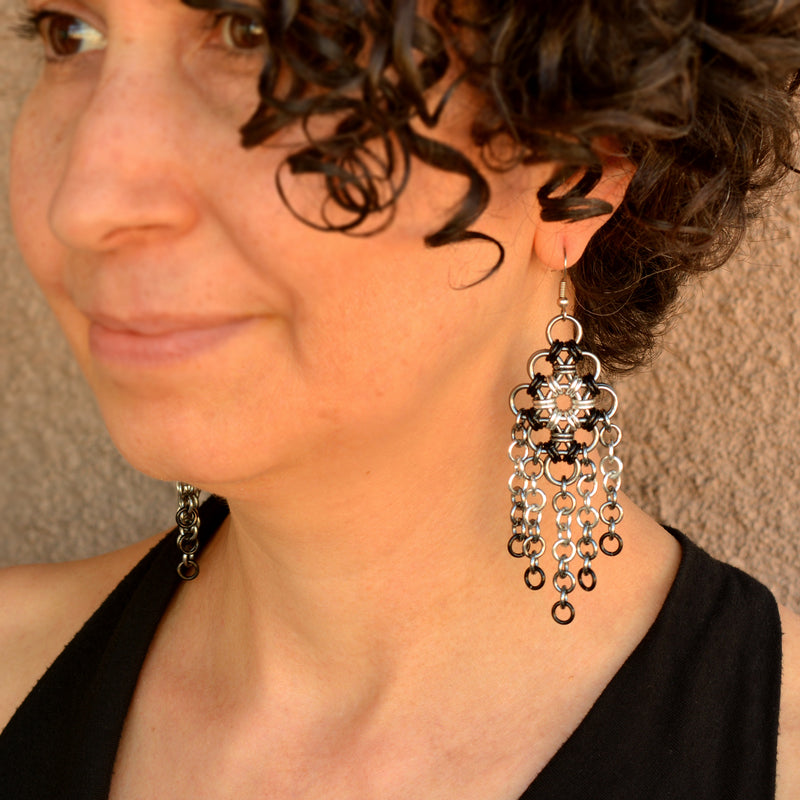 Black and white ombre chainmaille dangle earrings being worn by artisan Rebeca Mojica